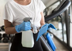 mujer guantes solucion limpieza gimnasio